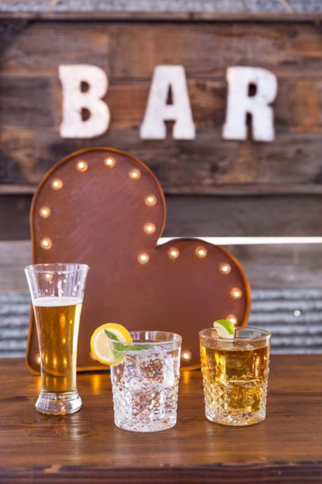 Beer Pilsner & Carat Rocks Glasses On Whiskey Barrel Bar With Barnwood Decor Wall & Bar Sign