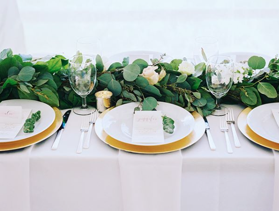 Simple white table setting with gold chargers