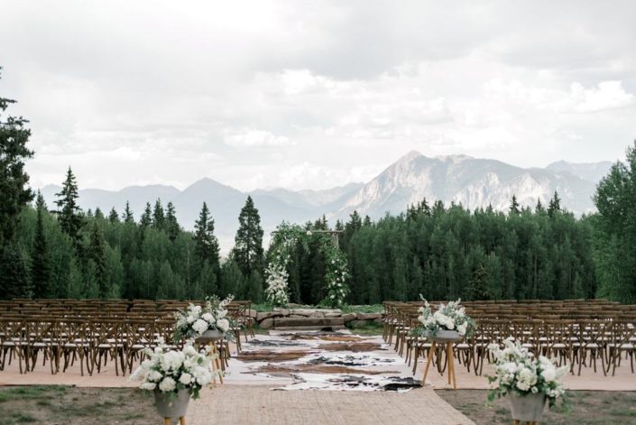 Colorado mountain wedding ceremony with x back chairs and wedding arbor rental