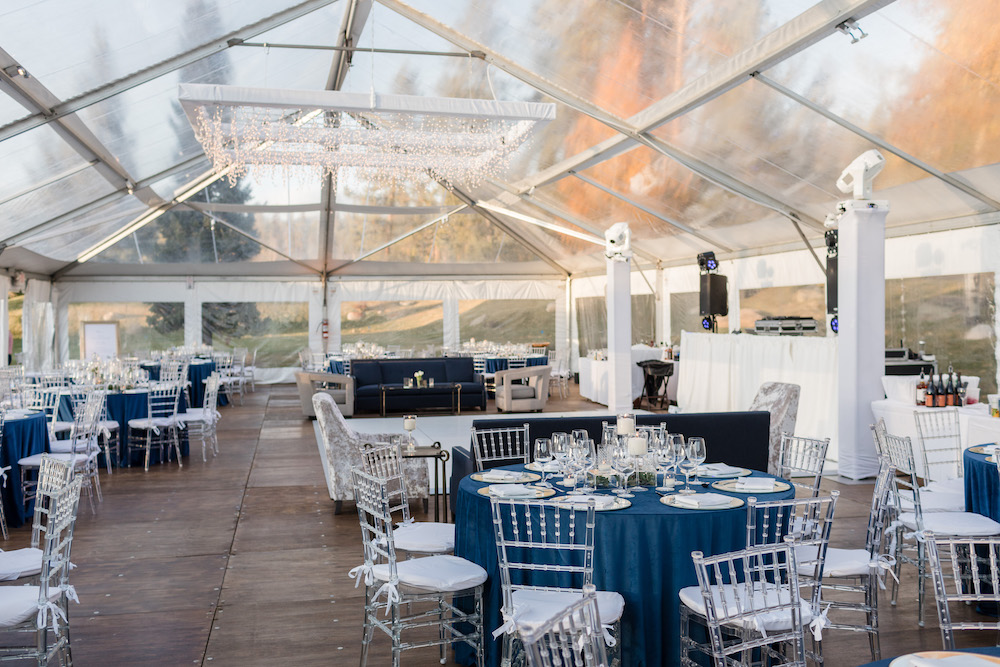 Clear wedding tent with clearn chiavari chairs and blue table clothes