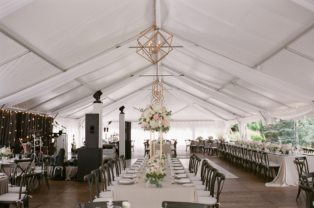 Larkspur wedding tent insight with farm tables