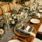 Gold rimmed chargers and blue wedding reception table design for Colorado mountain wedding