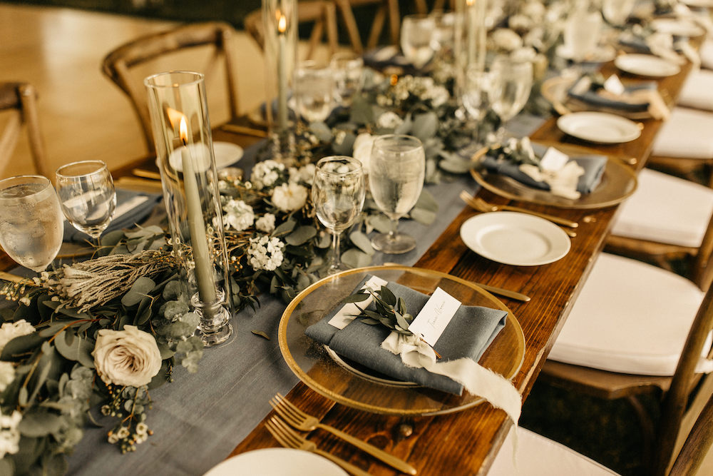 Gold rimmed chargers and blue wedding reception table design for Colorado mountain wedding