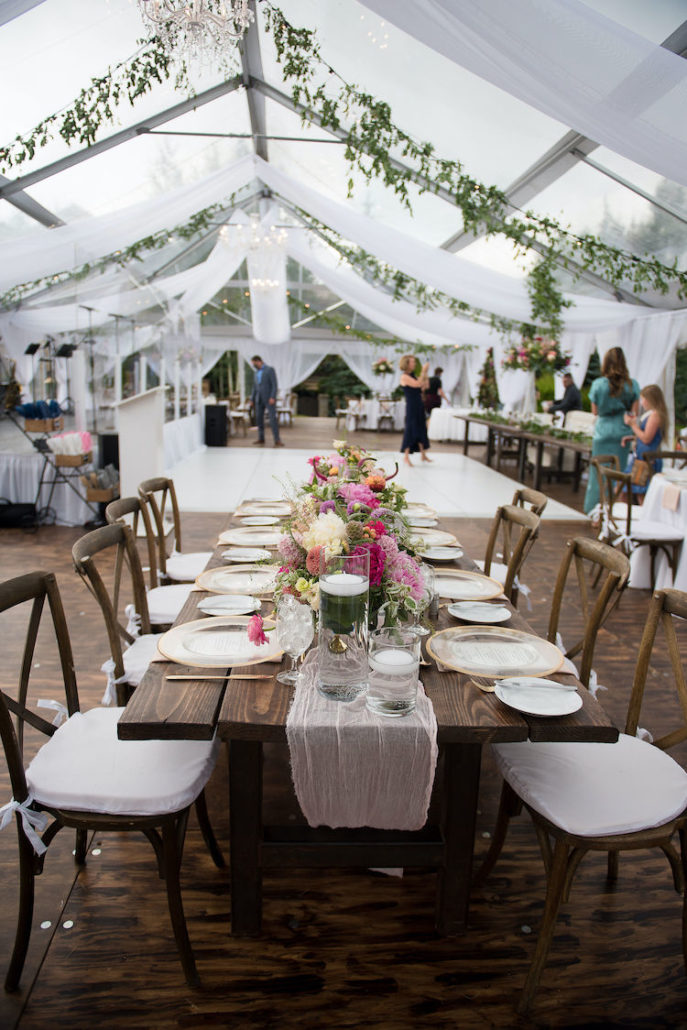 Clear wedding tent with fabric draping and farm tables in Colorado mountains