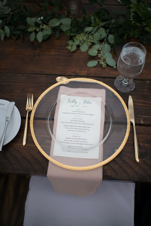 wedding table setting with gold rimmed charger and gold flatware